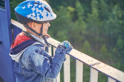 Rear view of boy holding umbrella against railing