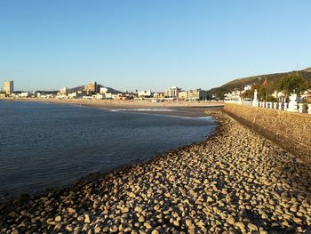 View of city street by sea against clear sky