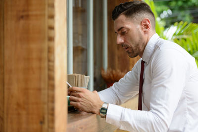 Side view of young man having coffee