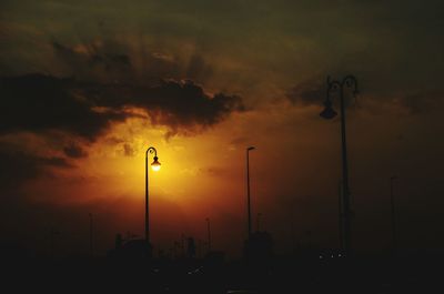 Low angle view of illuminated street light against cloudy sky