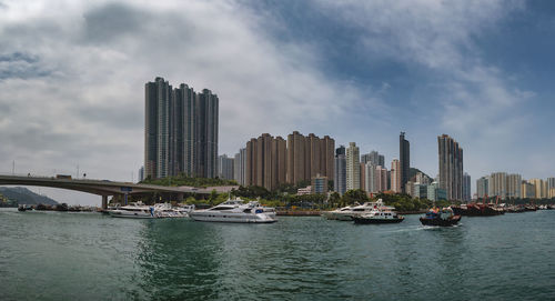 Modern buildings by river against sky in city