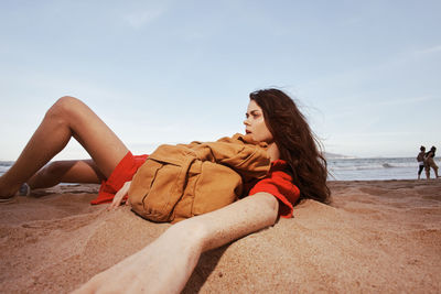 Young woman sitting on sand at beach