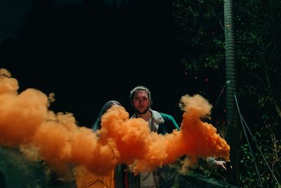 Man standing by woman holding distress flare at night