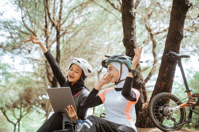 Smiling female friends listening music while sitting at park