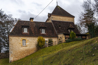 Exterior of old building by house against sky