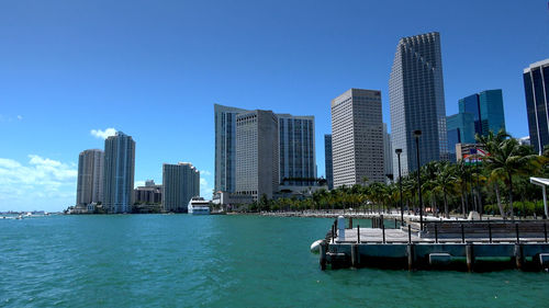 Sea by modern buildings against clear sky in city