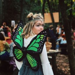 Portrait of young woman with make-up wearing butterfly costume outdoors