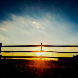 Silhouette field against sky during sunset