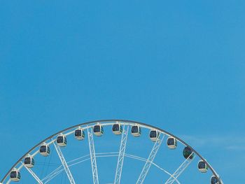 Low angle view of ferris wheel against clear blue sky