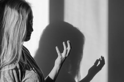 Close-up of woman with shadow on wall at home