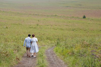 Rear view of couple walking on field