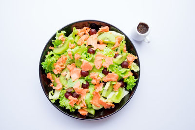 High angle view of chopped fruits in bowl against white background