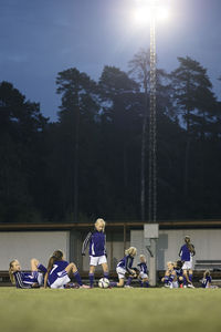 Surface level view of athletes relaxing on soccer field against trees