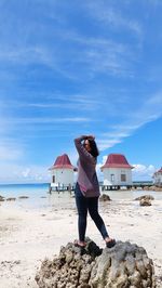 Rear view of woman standing on beach against sky