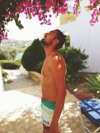 Side view of shirtless man standing outdoors