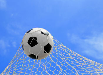 Soccer ball hitting in goal post against blue sky