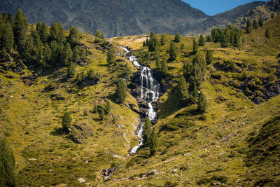 Scenic view of waterfall amidst trees and mountains