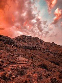 A man climbing on a mountain during sunset.