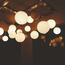 Low angle view of illuminated light bulbs hanging from ceiling