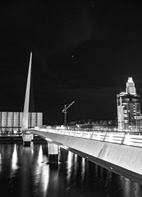 Bridge over river against buildings at night