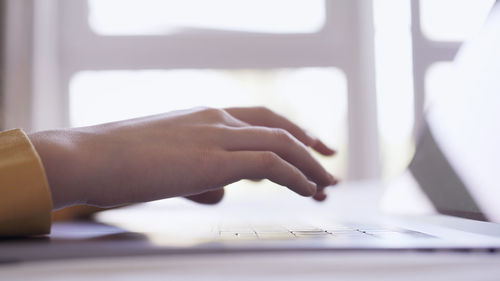 Cropped hands of woman using laptop