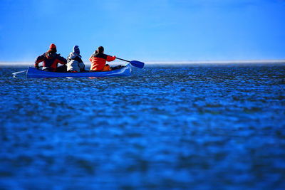 People enjoying sea trip against clear sky