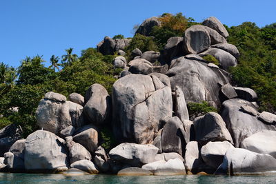 Rocks by sea against clear sky