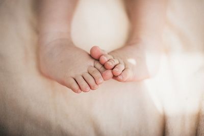 Low section of baby on bed at home