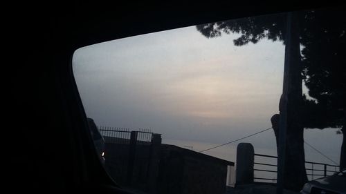 Silhouette of building seen through window at sunset