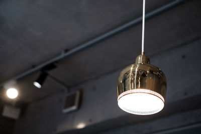 Low angle view of illuminated light bulb hanging from ceiling