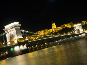 Illuminated bridge over river at night