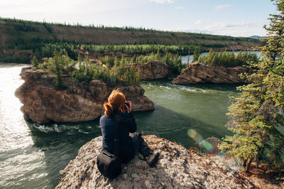 High angle view of mature woman sitting on cliff against river