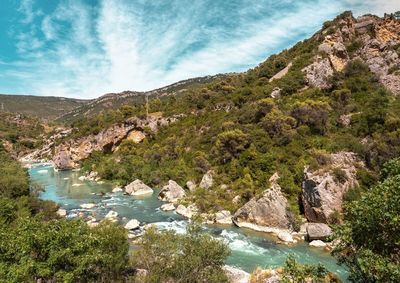 Scenic view of river by mountains against sky