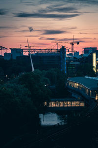 Bridge over illuminated city against sky at sunset