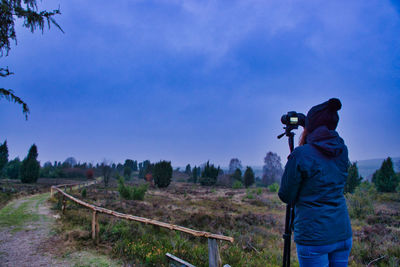 Rear view of man photographing against sky