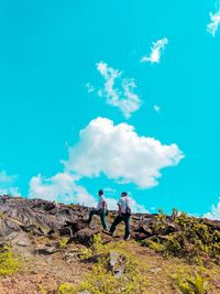 People standing on rocks against blue sky