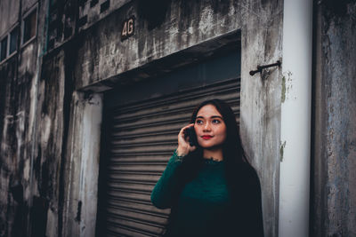 Woman talking on phone while standing by shutter