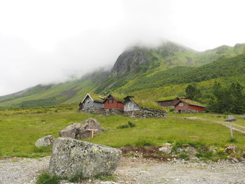 Houses on mountain by road against sky