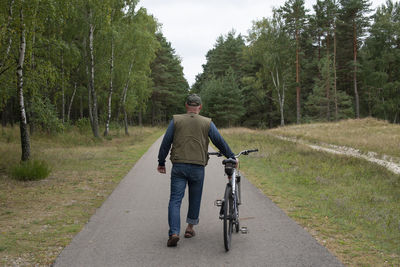 Rear view of man riding bicycle on field