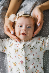 Mom's hands cover the face of a newborn daughter