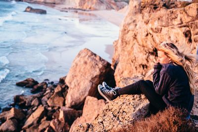 Woman sitting on rock by sea