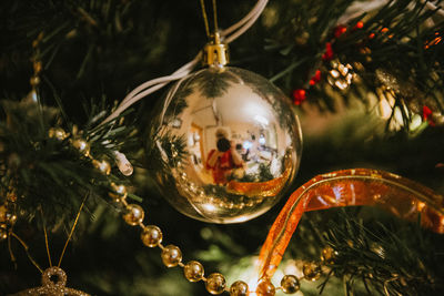 Close-up of christmas decoration hanging on tree with reflection of woman