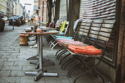 Empty chairs by tables at sidewalk cafe