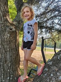 Portrait of happy girl on tree trunk