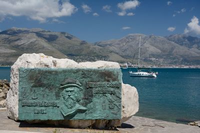 Nautical vessel on sea by mountains against sky