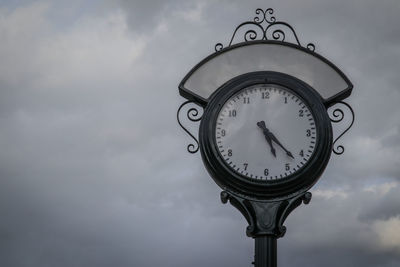 Low angle view of clock against sky