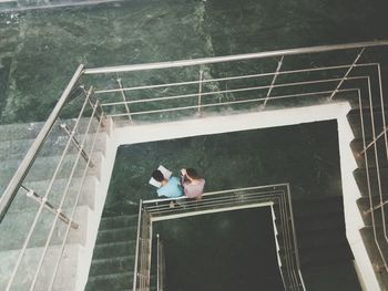 High angle view of people standing on steps by swimming pool