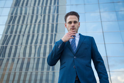 Low angle portrait of businessman standing against office building