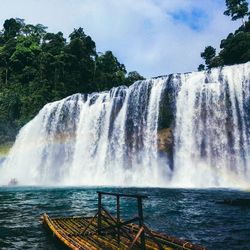 Scenic view of waterfall in forest against sky