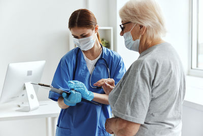 Female doctor wearing mask examining patient at clinic